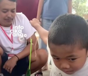 Seorang bocah tampak serius mengikuti lomba 17 Agustus dengan tantangan memasukkan sedotan ke dalam botol menggunakan kaca spion.